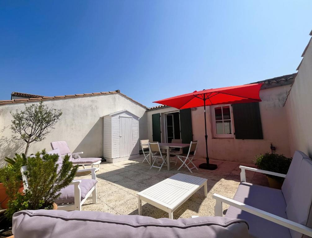 サン・マルタン・ド・レにあるAppartement VAUBAN proche plageのパティオ(テーブル、赤い傘付)
