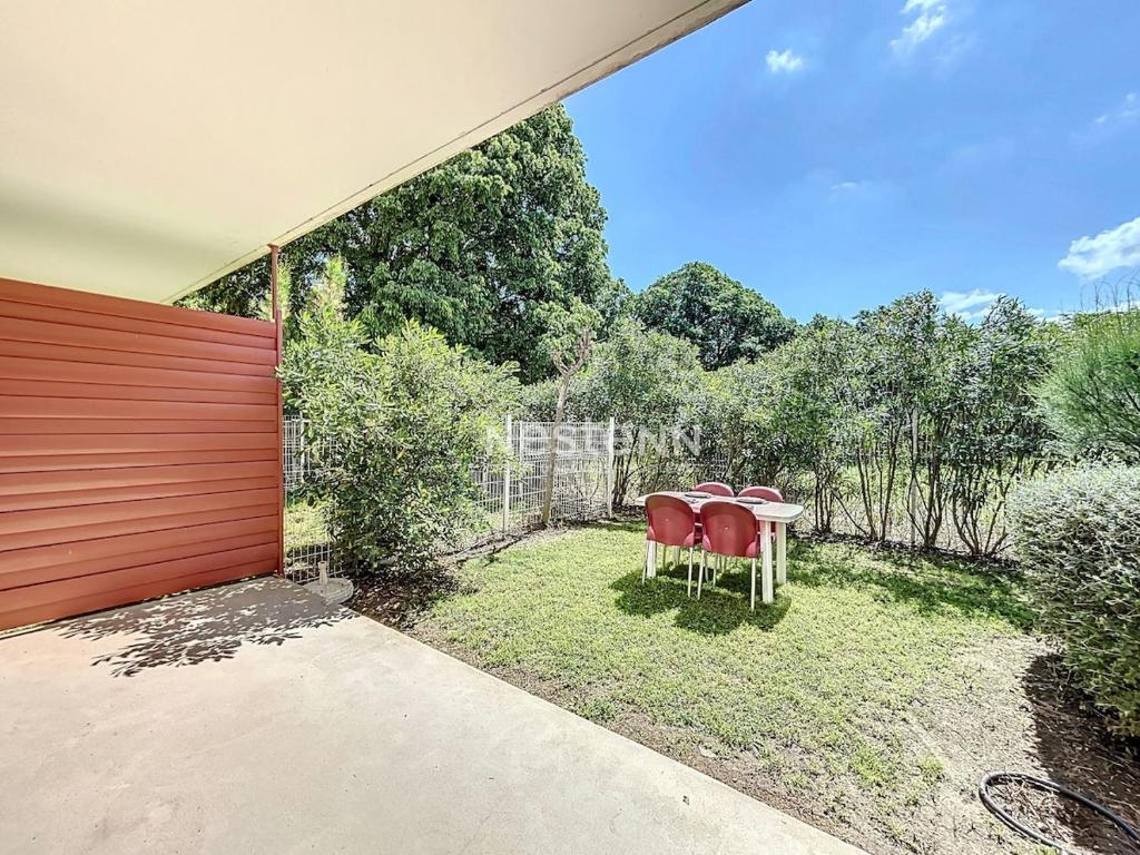 une image d'un jardin avec une table et des chaises dans l'établissement 3497-Appartement aux normes handicapés avec Piscine, à Argelès-sur-Mer