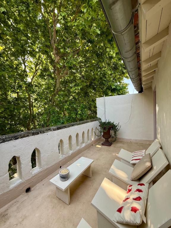 un patio avec des meubles blancs et un mur avec des arbres dans l'établissement Maison De La Major, à Arles