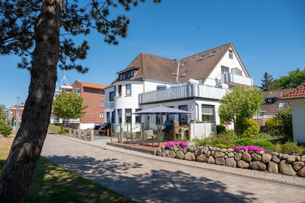 a white house with a table and umbrella in front of it at Hotel Villa Sonneck-Adults Only in Sankt Peter-Ording