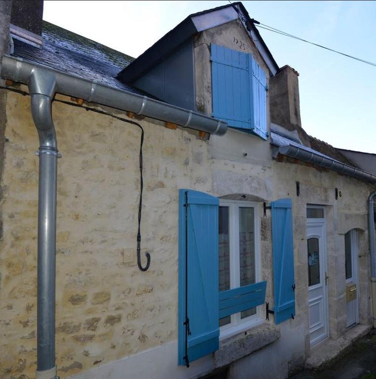 Un vieux bâtiment avec des volets bleus dessus dans l'établissement Butterfly Cottage, à Pouilly-sur-Loire