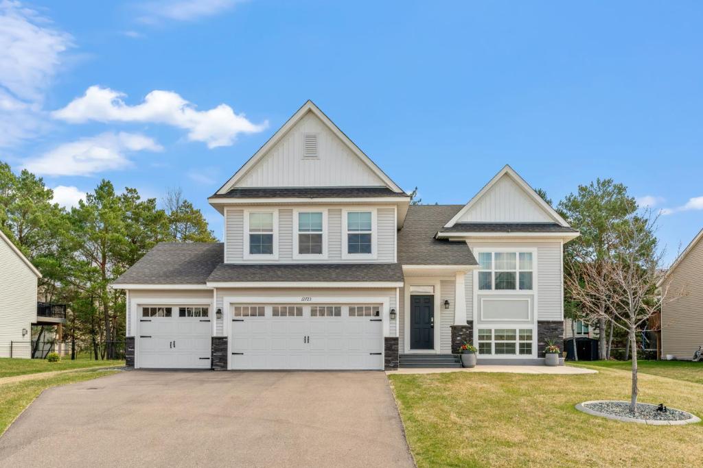 a house with white garage doors at Savanna Grove in Blaine
