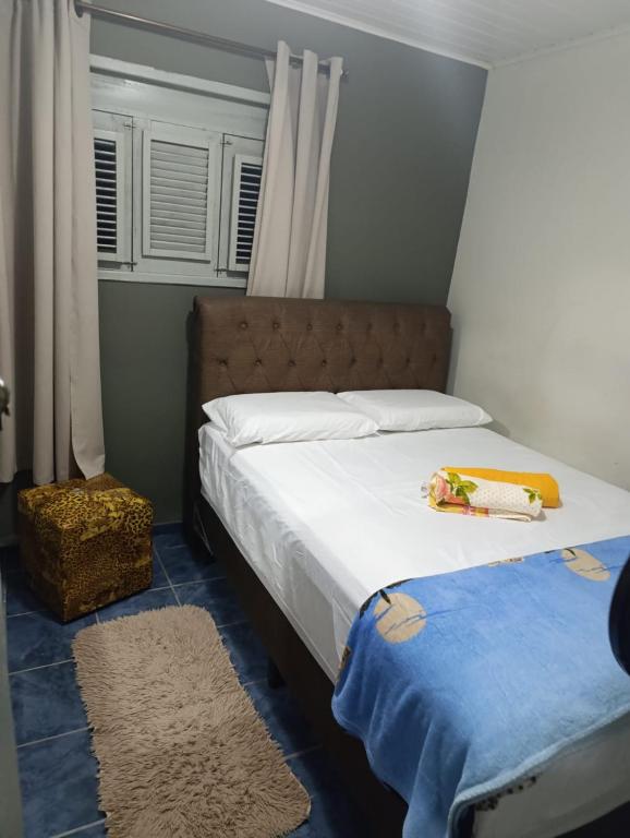 a bedroom with a bed with white sheets and a blue floor at Hostel da Val in Martins