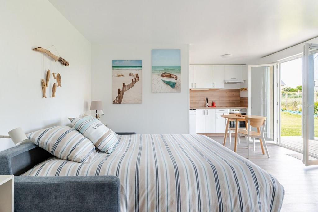 a white bedroom with a bed and a kitchen at Sardine argentée Plage à 100m Surf Randos GR 223 Jardin in Surtainville
