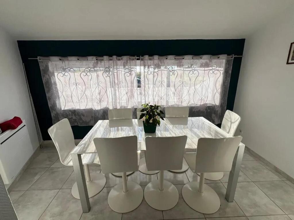 a dining room with a table and chairs and a window at Charmante maison à Lagord avec jardin privatif in Lagord