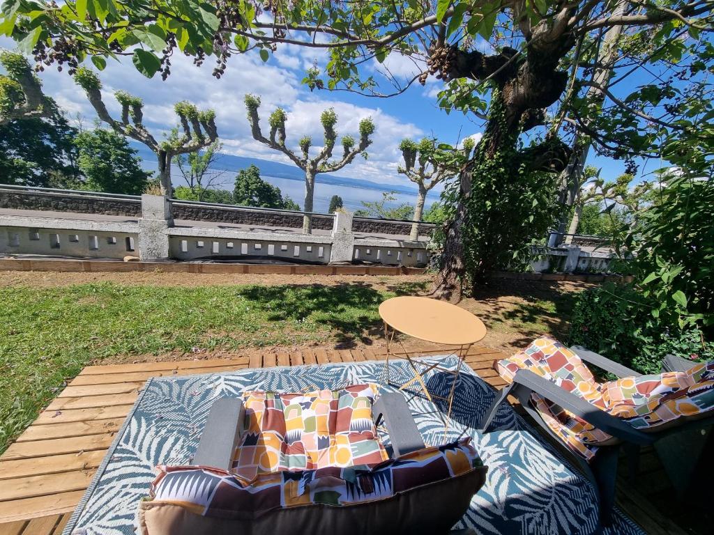 a patio with a couch and a table on a deck at Appartement Cozy 2 Panoramique Lac Léman Thonon-Les-Bains in Thonon-les-Bains