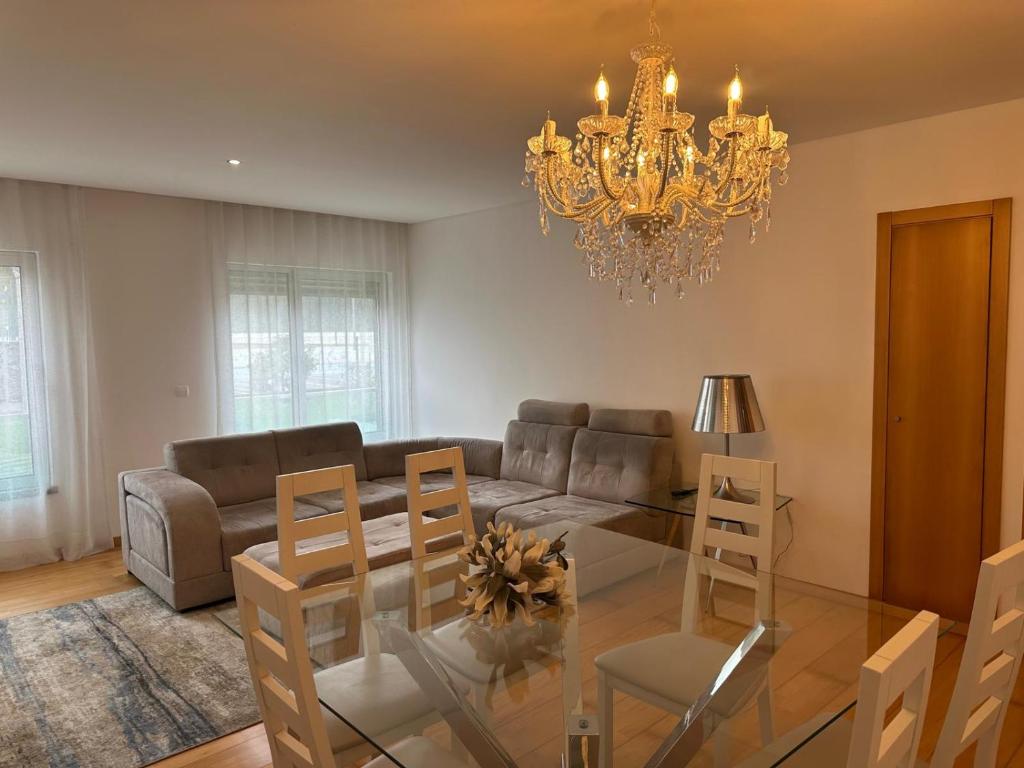 a living room with a glass table and a chandelier at Azores Lava Apartment T3 in Ponta Delgada