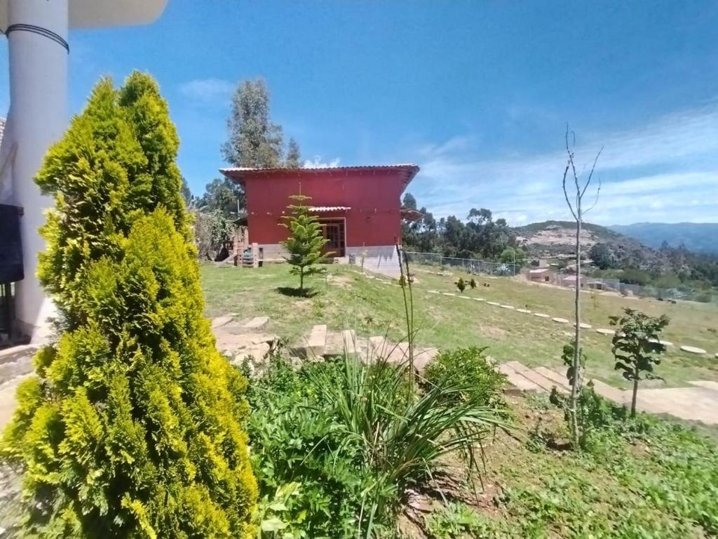 ein rotes Haus auf einem Hügel mit gelben Blumen in der Unterkunft Hospedaje El Tayo - Casa de campo Cajamarca in Cajamarca
