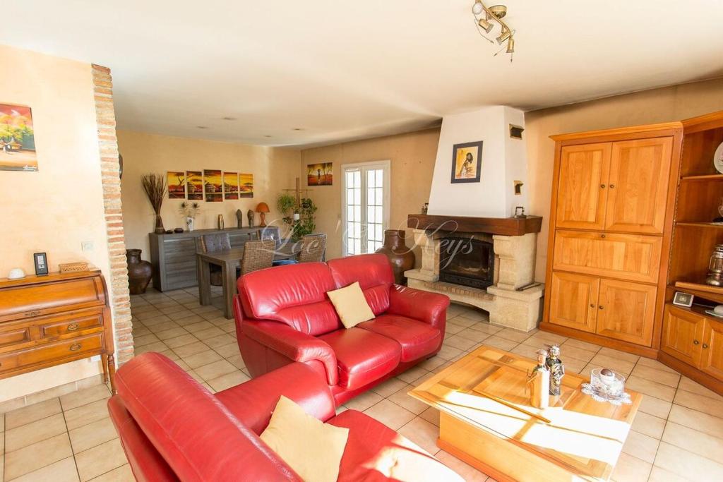 Il comprend un salon doté d'un mobilier en cuir rouge et une cuisine. dans l'établissement Maison landaise, à Biscarrosse