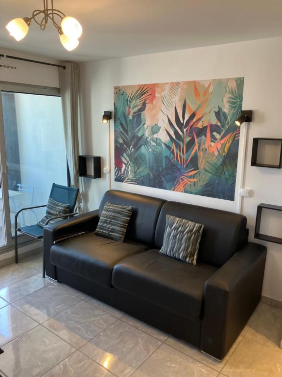 - un canapé noir dans le salon orné d'un tableau dans l'établissement Studio des Quilles, à Sète