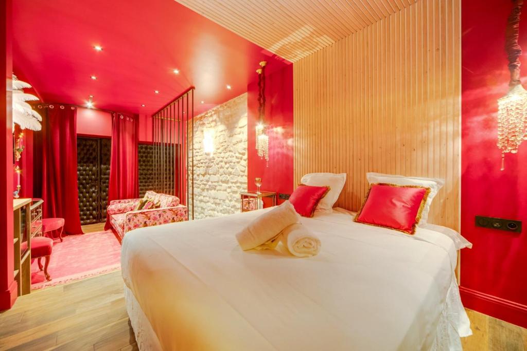 - une chambre avec un grand lit blanc aux murs rouges dans l'établissement Love & Room SPA Week-End, à Paris