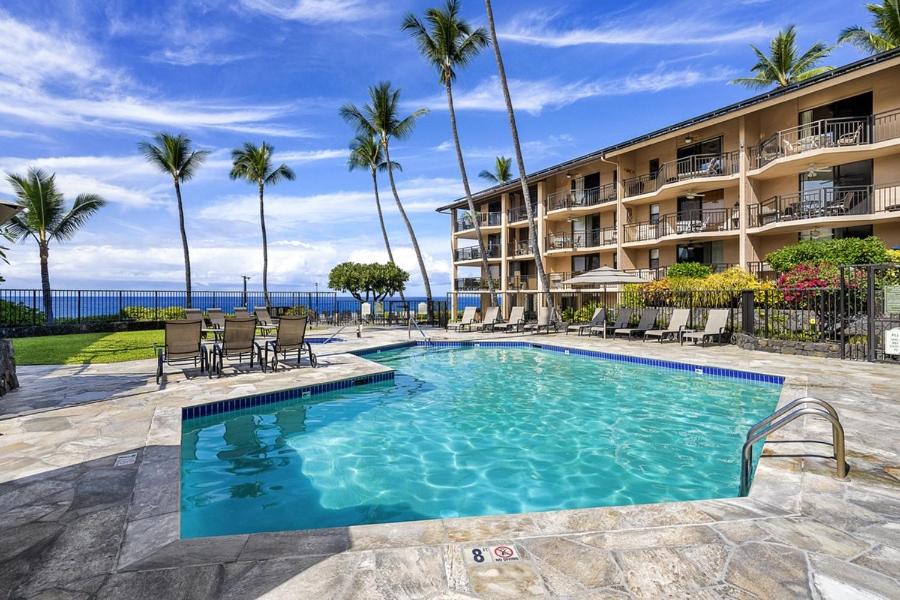 a swimming pool in front of a hotel with palm trees at Kona Makai Private Tropical Suites with Pool in Kailua-Kona