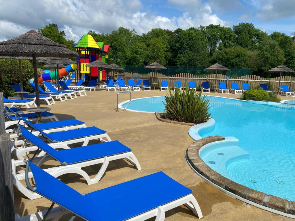 - une piscine avec des chaises et un toboggan dans un complexe dans l'établissement Mobil Home, à Clohars-Carnoët