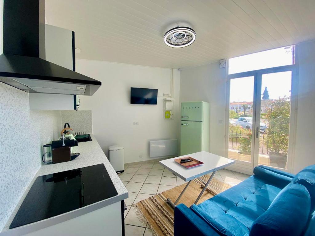 a living room with a blue couch and a kitchen at Villa Salve Maria, proche plage et centre ville, ménage et draps compris in Arcachon