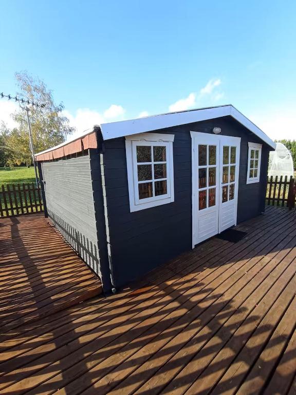 - un bâtiment bleu et blanc sur une terrasse en bois dans l'établissement loue chalet calme tout équipé, à Madaillan