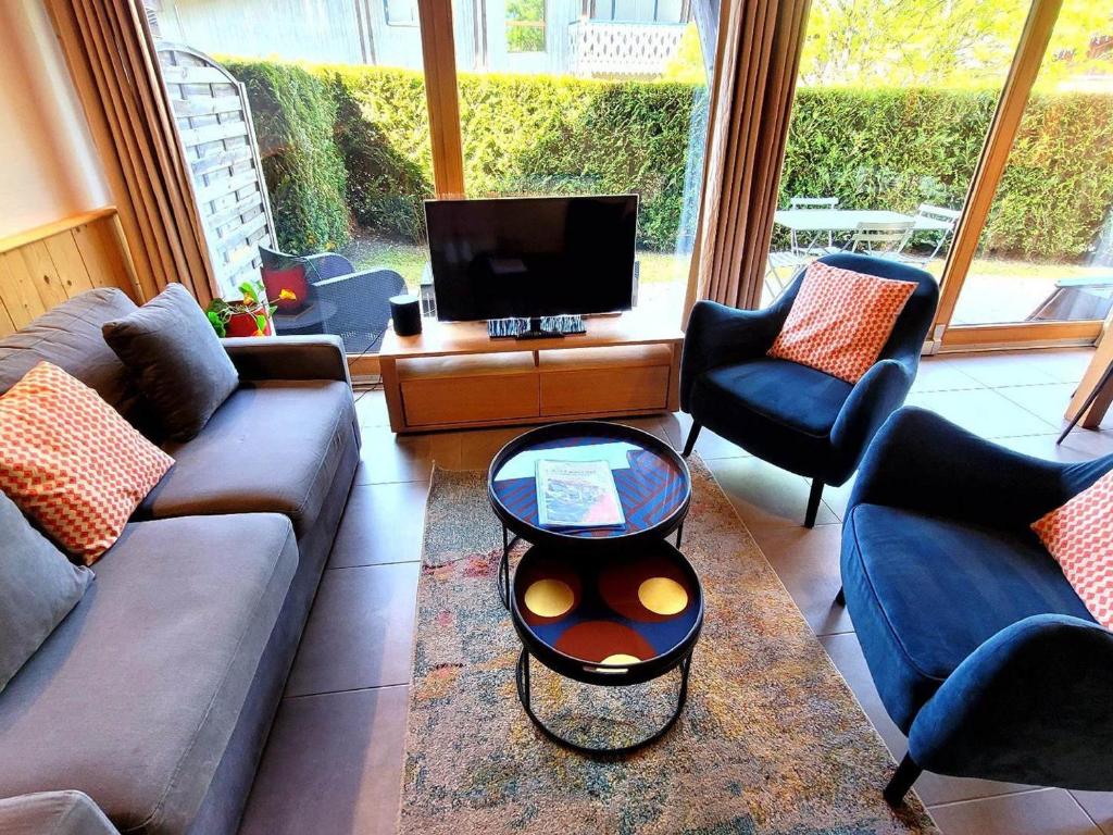 un salon avec un canapé, des chaises et une télévision dans l'établissement Appartement duplex 3 pièces près des pistes, jardin, terrasse, Wi-Fi, parking couvert - FR-1-598-80, aux Gets