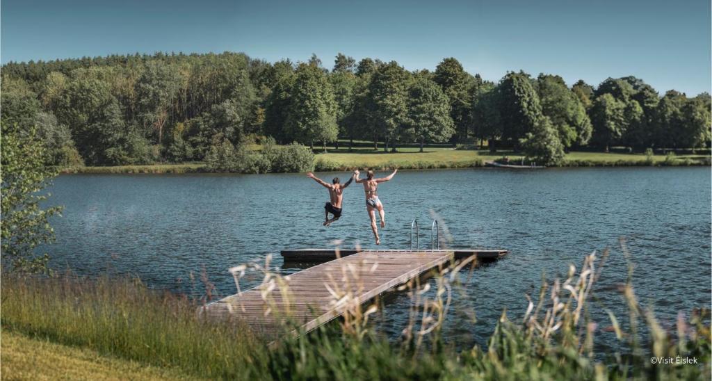 two people jumping off a dock into a lake at Anatura Luxembourg in Weiswampach