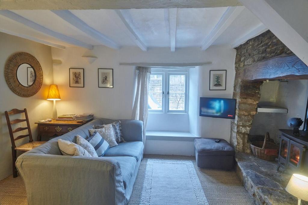 ein Wohnzimmer mit einer blauen Couch und einem Kamin in der Unterkunft Cosy Cottage in Kings Sutton
