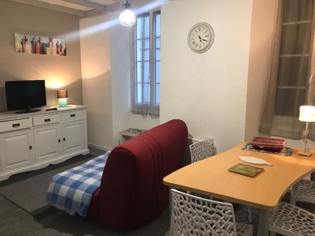 a room with a table and a chair and a clock at La SOURCE FROIDE in Eaux-Bonnes