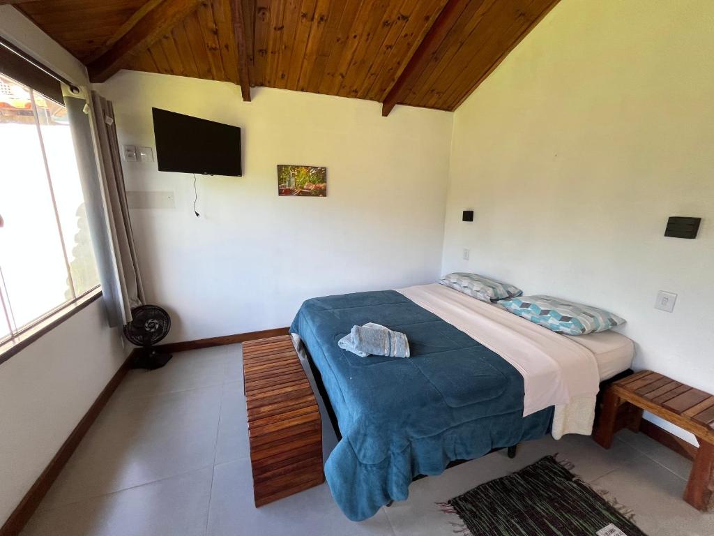 a bedroom with a bed and a flat screen tv at Chalé Lírio do Campo in Lavras Novas