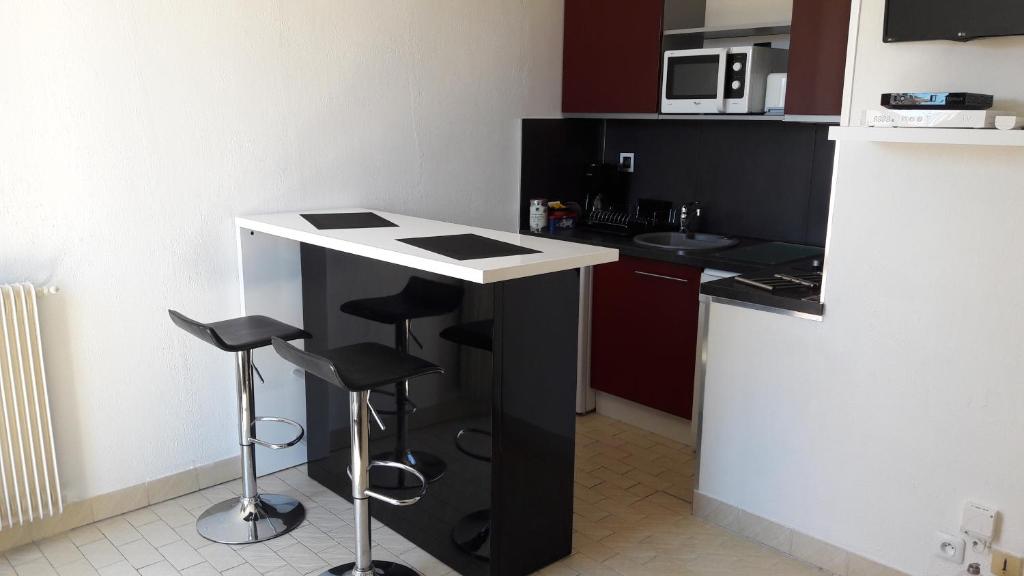 una cocina con encimera y taburetes en blanco y negro en Appart Le Massillon Arenes Centre, en Nimes