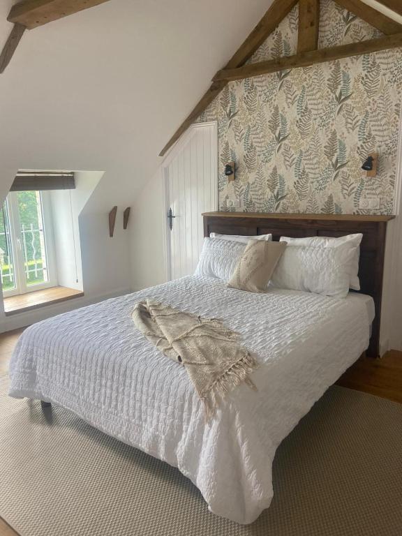 une chambre avec un grand lit avec des draps et des oreillers blancs dans l'établissement Pinabre Rose Cottage, à Plouguenast Langast