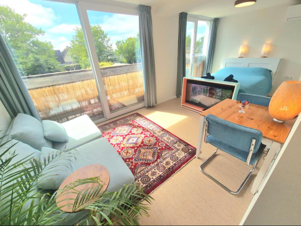 a living room with a couch and a table and a television at Welkom Op Texel privé kamer op het zuiden in De Koog