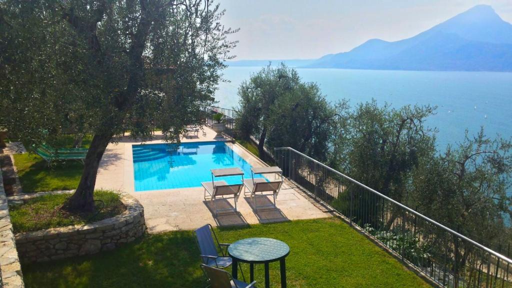 a swimming pool with a table and chairs next to the water at Agricampeggio Relax (Campsite) in Brenzone sul Garda