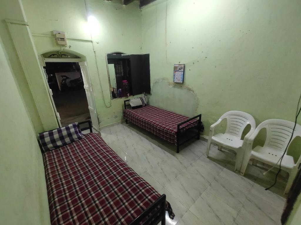 une vue aérienne d'une pièce avec deux lits et deux chaises dans l'établissement Mohak Yatri Nivas मोहक यात्री निवास, à Kolhapur