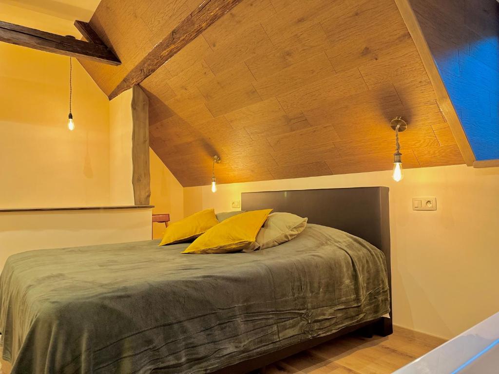 Un dormitorio con una cama grande con almohadas amarillas. en Le Ruisseau Gîte Idéal pour un Séjour à Deux au Fil de l'Eau, en Vireux-Wallerand