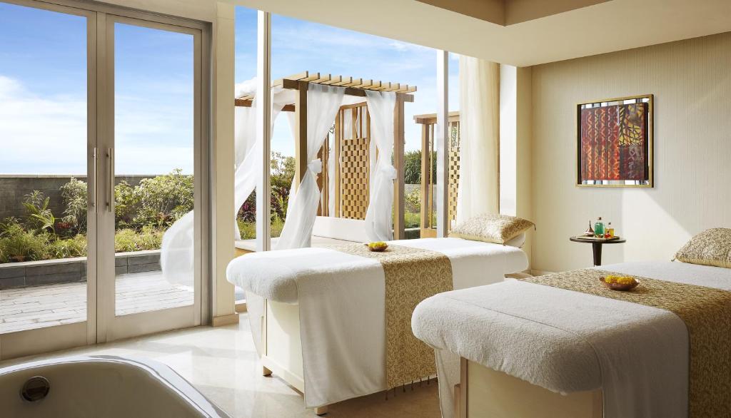 a room with two beds and a tub and a window at Taj Bangalore in Devanahalli-Bangalore