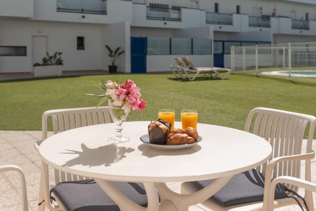 a white table with a plate of food and two glasses of orange juice at Casita Lola in Costa Calma