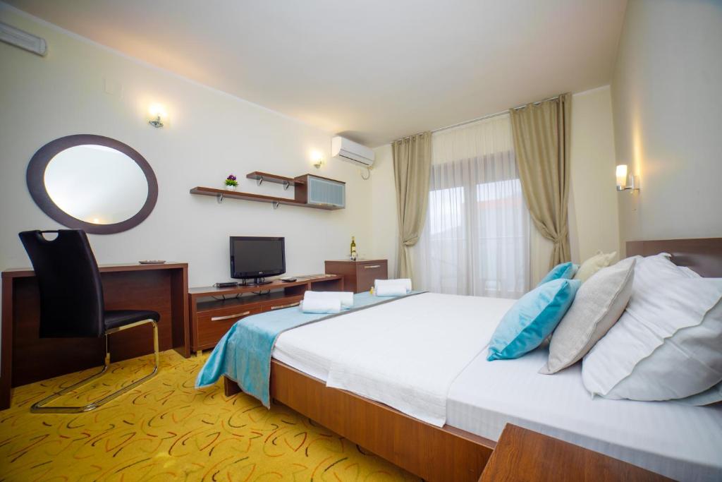 a bedroom with a bed and a desk and a mirror at Hotel Odissey Jaz in Budva