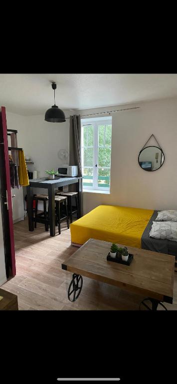 une chambre avec un lit jaune et une table dans l'établissement Studio coeur de ville, à Figeac