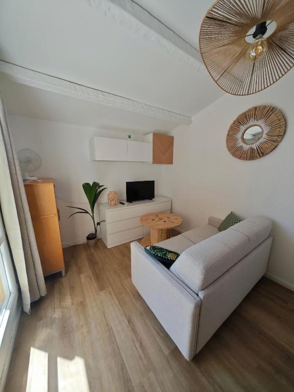 un salon avec un canapé blanc et une télévision dans l'établissement L'abri-côtier, au Cap d'Agde