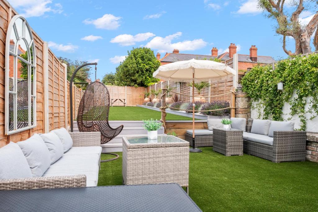 a patio with wicker furniture and an umbrella at Bay View Luxury Stays - Iris Harbour Cottage in Rodwell
