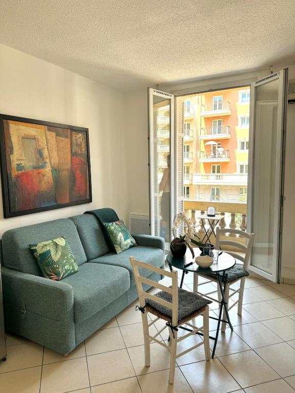 un salon avec un canapé bleu et une table dans l'établissement Magnifique 2 pièces à côté de la mer, à Nice