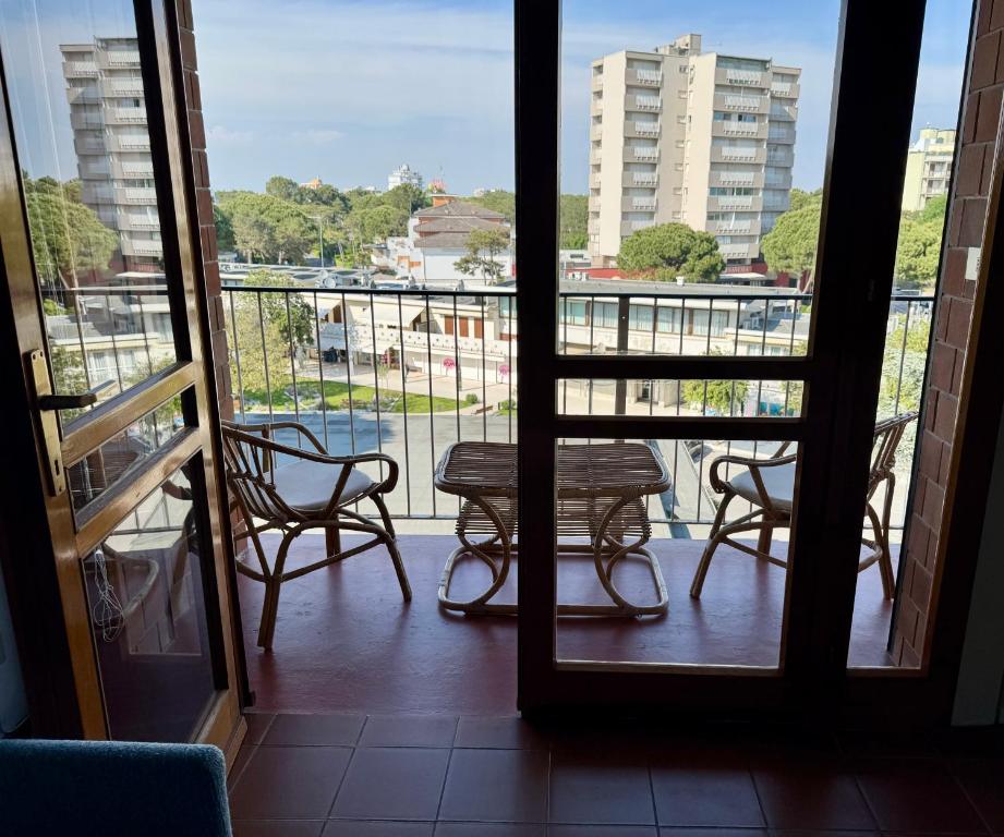 a room with a balcony with a table and chairs at Ampio appartamento in centro con vista - terrazze, parcheggio gratuito e Wi-Fi in Lignano Sabbiadoro