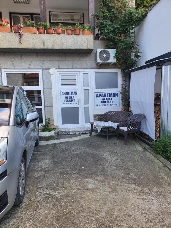 a car parked in front of a building with a bench at APARTMENT Marash in Prizren