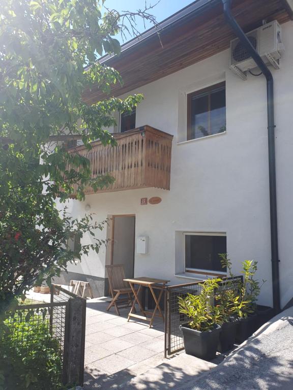 una casa con balcone e tavolo nel cortile di ALPINE VILLAGE APARTMENT with a private terrace, garden, and parking - at a walking distance from LAKE BLED a Bohinjska Bela