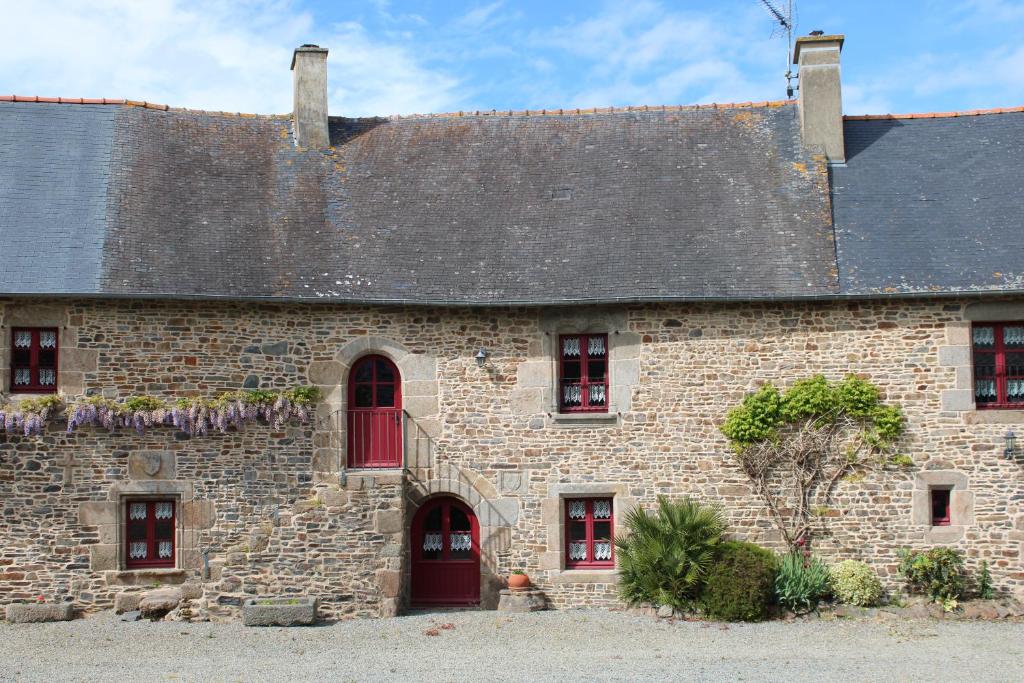 a large brick building with red windows and a roof at La Maison Bienvenüe - Baie du Mont Saint Michel in Baguer-Pican