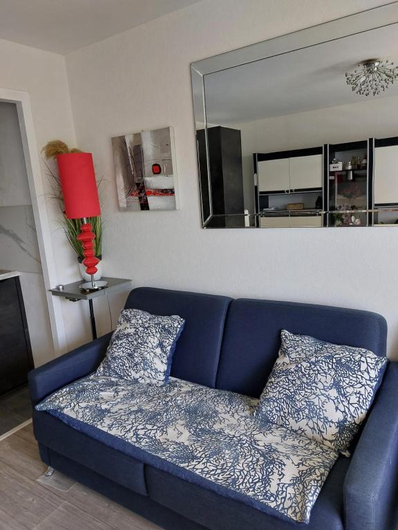 un canapé bleu dans un salon avec un miroir dans l'établissement Studio 50M plage, à La Baule
