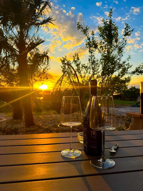 a bottle of wine and two glasses on a table with the sunset at Stressless Nin in Nin