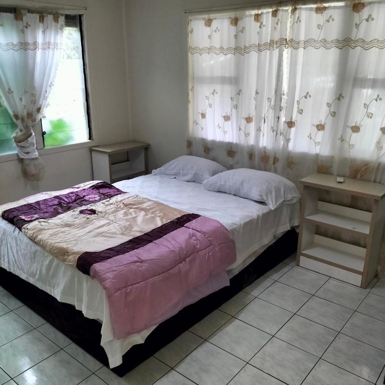 a bedroom with a bed and a window with curtains at Nukuma'anu Vic's Guests house in Nuku‘alofa