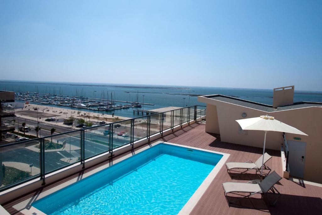 a swimming pool on a balcony with a view of the ocean at Real Marina Residence in Olhão