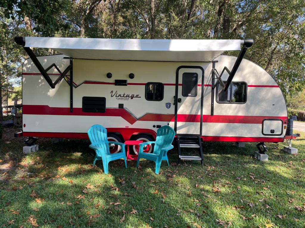 an rv with two blue chairs in front of it at Retro camper in Ocala