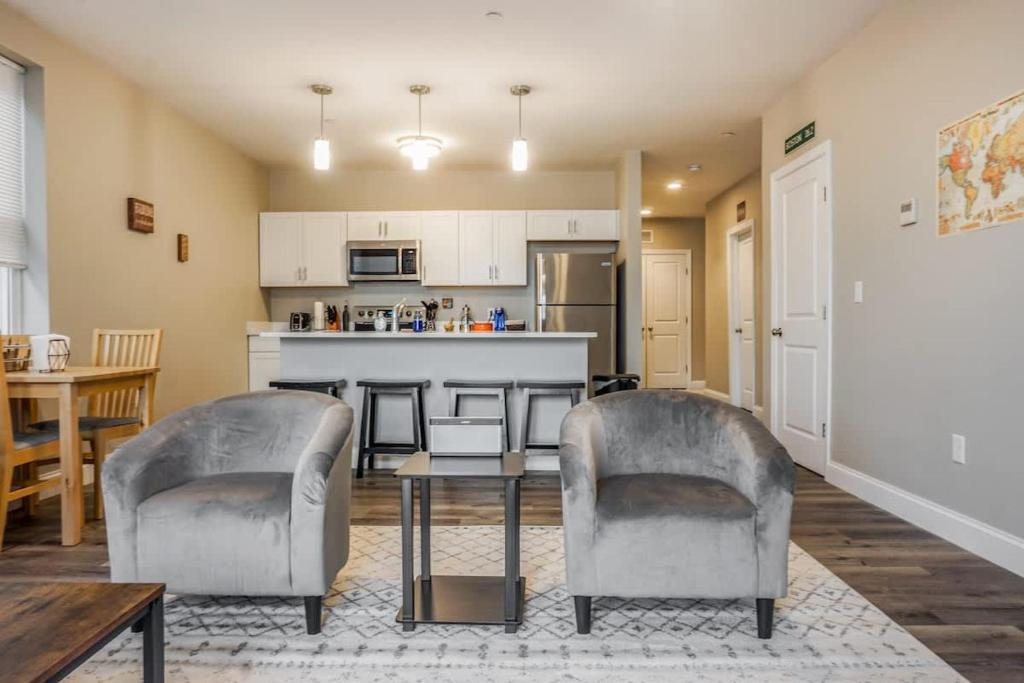 a living room with two chairs and a kitchen at Unit 22 Luxurious 1BR Apartment Long-term stays in Chelsea