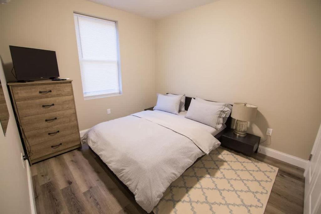 a bedroom with a bed and a dresser with a television at Unit 23 Comfy 1BR Apartment Long-term stays in Chelsea