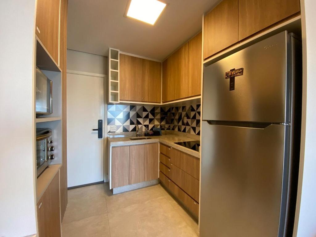 a kitchen with a stainless steel refrigerator and wooden cabinets at 20 floor perfect view Brooklin in Sao Paulo
