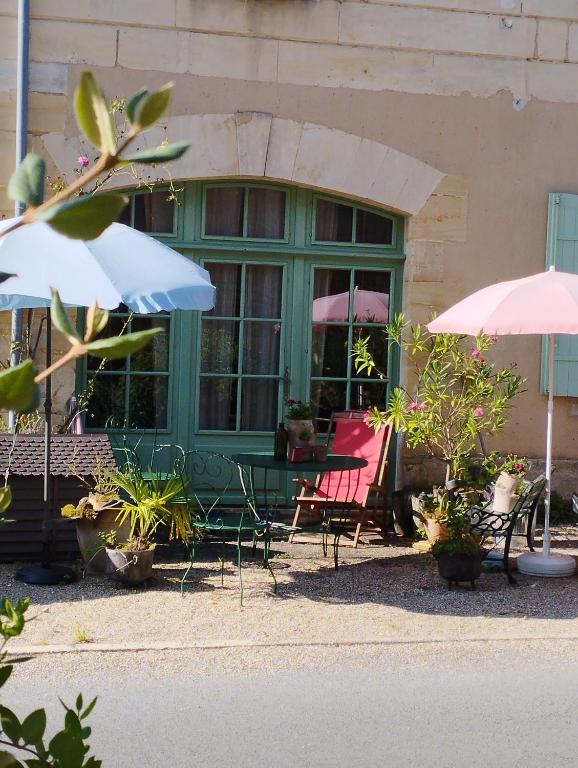 un groupe de chaises et de parasols devant un bâtiment dans l'établissement Aux chambres du bourg, à Saint-Avit-Sénieur